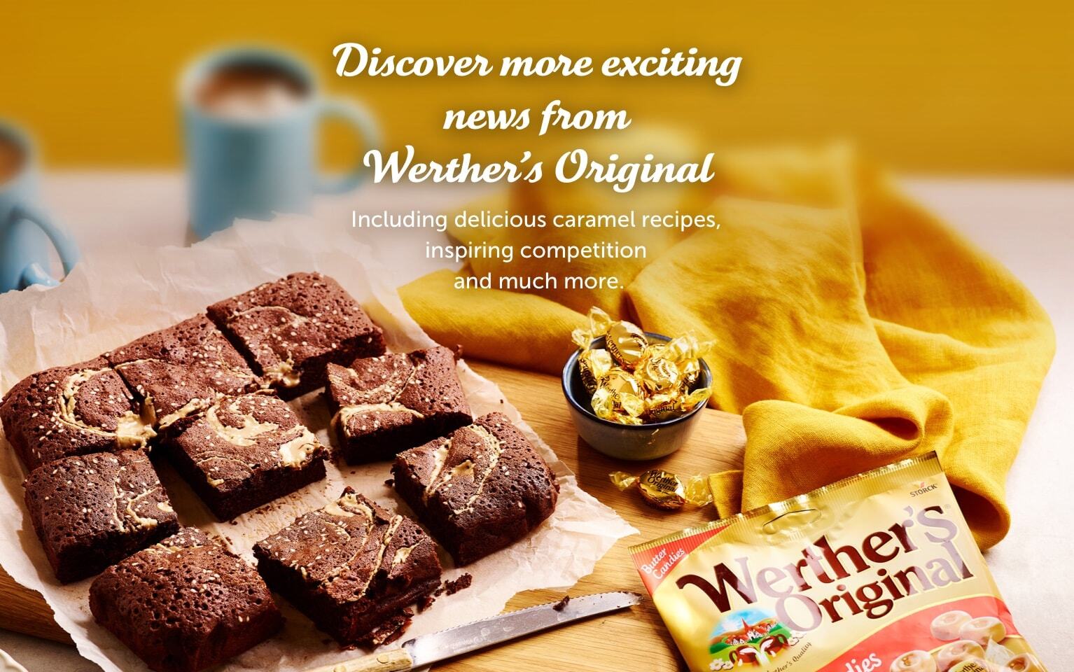 Squares of caramel brownies on baking paper, with a bowl of golden-wrapped Werther’s Original candies, a cup of coffee, and a Werther’s Original package on the side.